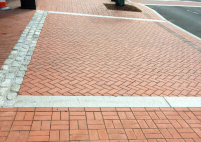 Commercial masonry construction project, brick pedestrian walkway and main driveway entrance in front of the apartment building leading to resident and visitor parking, stone decorative border clearly marks driving lane, located in Norwalk, Connecticut.