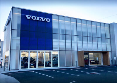 Commercial masonry construction project for a Volvo car dealership, new paved asphalt parking lot with drains and white lines to clearly mark customer parking.