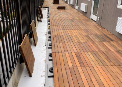 Commercial masonry project, large modern rooftop terrace or balcony of a building overlooking the city, installation of wooden decking tile.