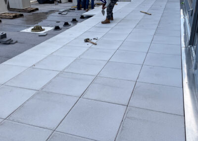 Commercial masonry project, large rooftop terrace or balcony of a building overlooking the city skyline, installation of stone decking.