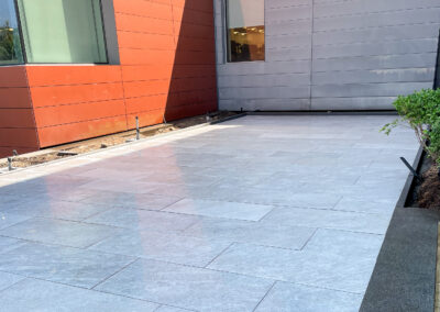 Commercial masonry construction project, small modern stone patio of an office building with patio drains.