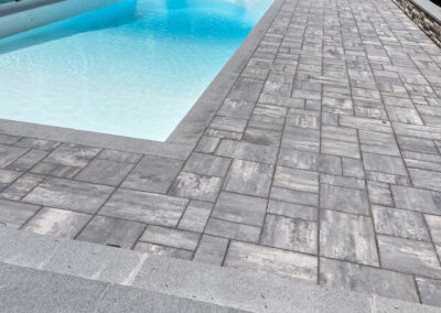Contemporary residential pool renovation with stone coping and modern stone pool patio in random pattern.