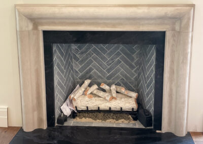 Contemporary indoor fireplace renovation with smooth natural wood mantel and sleek herringbone tile.