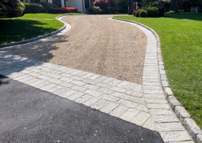 Modern, minimalist residential gravel driveway renovation with block border, decorative entrance pattern and band detail.