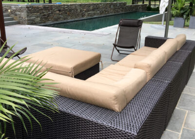 Modern residential pool and surround renovation features stone coping, stone pool patio, and stacked stone retaining wall.