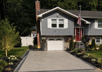 Newly installed brick paver driveway featuring a detailed, dark contrasting border design along the edge.