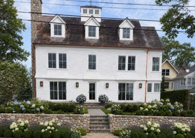 Front entrance landscape design featuring a rock-face retaining wall, stone paver walkway, matching front porch steps, and beautiful garden beds.