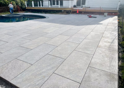 Polished residential pool and surround renovation features sleek stone pool patio.