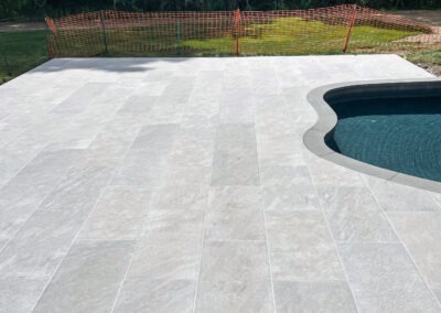 Polished residential pool and surround renovation features sleek stone pool patio.