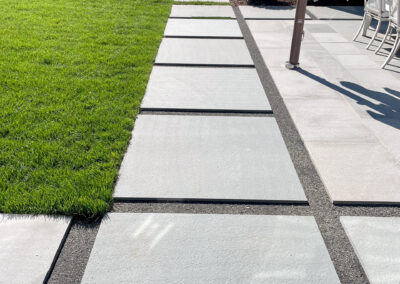 Modern residential stone patio renovation with sleek stepping stone walkway leading to pool area and outdoor dining.