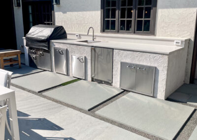 Modern residential stone patio renovation with sleek stepping stone walkway leading to outdoor dining and outdoor kitchen.
