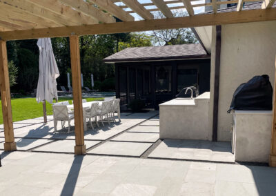 Residential stone patio renovation with stepping stone walkway leading to pool area, outdoor dining, and outdoor kitchen.